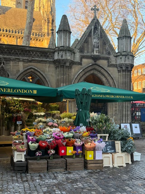 A floral display outside a historic stone church features a variety of fresh flowers arranged in colorful bouquets and wrapped in pastel and vibrant paper, with some in small white buckets and others